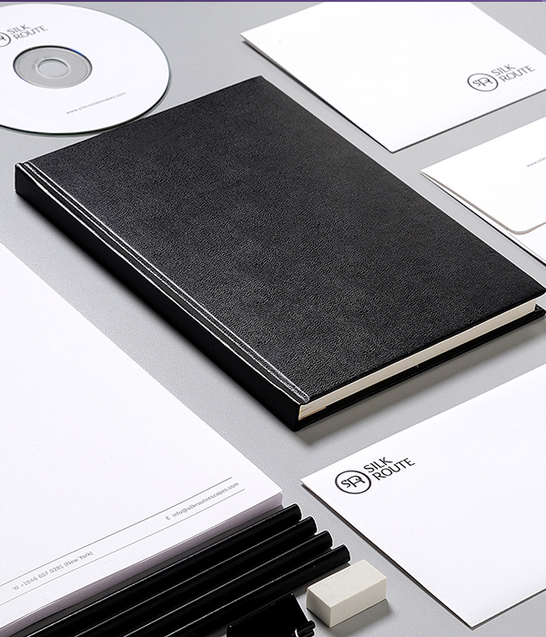 Professional corporate branding for Silk Route Escapes, 
                including a black leather-bound notebook, a CD, white envelopes, and letterheads with the company logo.