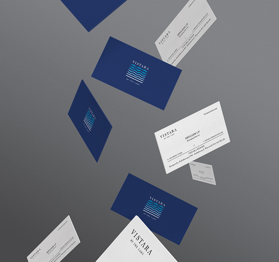 Floating Vistara by the Lake business cards in blue and white with wave logo, styled mid-air on gradient background to emphasize resort's elegant branding and premium experience
